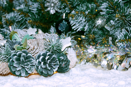 Christmas background with Christmas tree branches, wreath of cones and silver tinsel in the light of golden garlandの写真素材