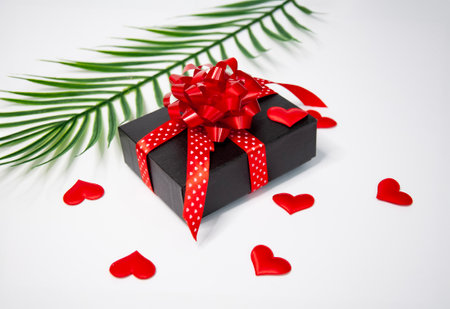 Black gift box with red ribbon and heart on a white background.の写真素材