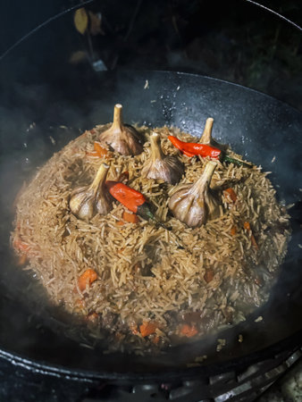 Spiced Pilaf with Garlic Bulbs and Chili Peppers â Steaming Rice Dish in Black Wokの写真素材