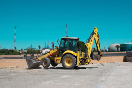 yellow excavator bulldozer on concrete surface against blue skyの写真素材