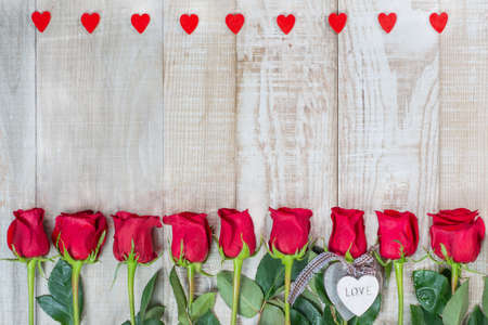 frame of hearts and red Dutch varietal roses freedom on a light wooden surface. Floral outline with wooden hearts. Idea for Valentines Day.Congratulations to women, mothersの写真素材