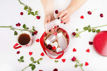 female hands with beautiful fashionable manicure holding a tube of cream. Cosmetics tube of cream inside the decorated box .Presentation of cosmetic bottles for cream. Womens cosmetics in a box on a background of flowers. Hand holding tube .の写真素材