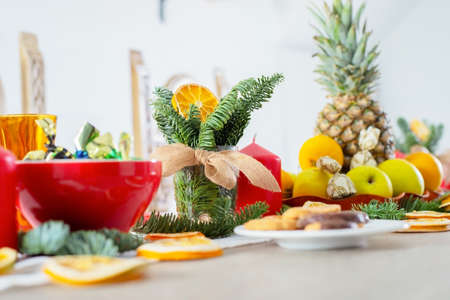 Christmas festive table is decorated with candles, Christmas tree branches, dried oranges, beautiful...