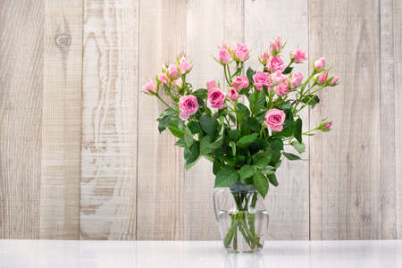 bouquet of bouquet pink roses in water in a glass vase wooden backgroundの写真素材