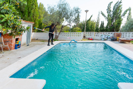 Woman preparing and cleaning the pool for the swimming area with water vacuum cleaner in the handsの写真素材
