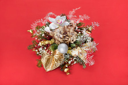 winter Christmas composition for the house from twigs,balls,artificial snow,luminous garland,bow,flowers on a red background with the effect of falling snow for your projectの写真素材