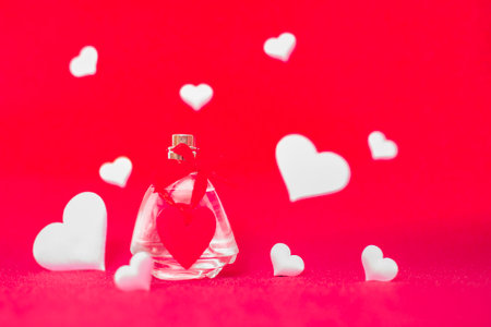 bottles of womens perfume with a gift ribbon among hearts on a red background gift card for Valentines Dayの写真素材