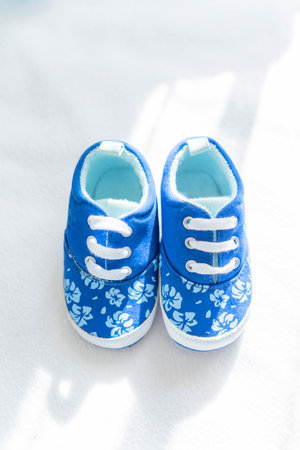 childrens little shoes on a light background, in sunlight, isolated, shadows from the window. Showcase of a childrens store. Presentation of childrens shoes.の写真素材