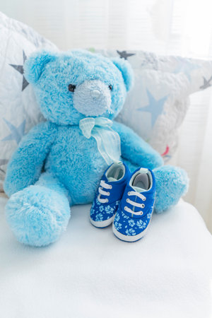 childrens bed with a teddy blue bear and childrens small shoes nearby, childrens room interior. Childrens accessoriesの写真素材