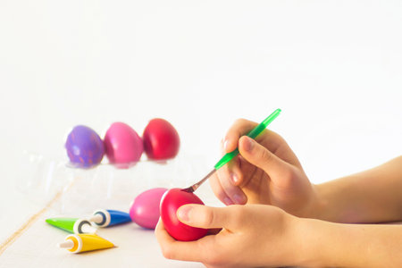 Easter egg coloring process with a brush of acrylic paints.two hands paint eggs close-up with a bright paint brush.Handmade,hobbyの写真素材