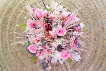beautiful delicate bouquet of stabilized flowers, roses, dried flowers, twigs of leaves against the background of a rustic style carpet, isolated, close,selective focus. bridal bouquet, gift bouquetの写真素材