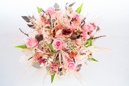 a beautiful delicate bouquet of stabilized flowers, roses, dried flowers, twigs of leaves on a light background is isolated, close ,selective focus. bridal bouquet, gift bouquetの写真素材