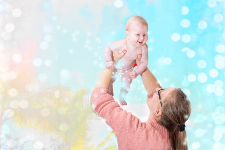 mother plays with a newborn laughing child, throws it over her head against the backdrop of nature and blurry glare of lights. Happy family concept, mothers day, childrens dayの写真素材