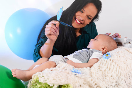 happy woman, smiling, playing with a child. mother entertains toddler playing with bow tie.child care concept.Mothers Dayの写真素材