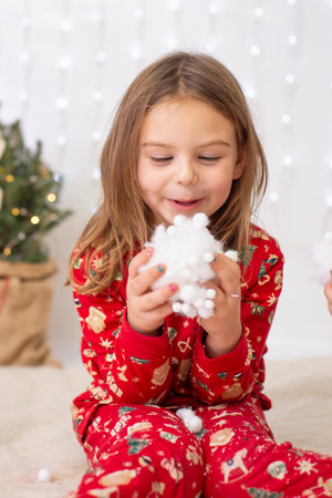 girl child in a New Years costume holds a snow globe made of lumps of snow against the background of a decorated Christmas tree and holiday lights and gifts,childrens partyの写真素材