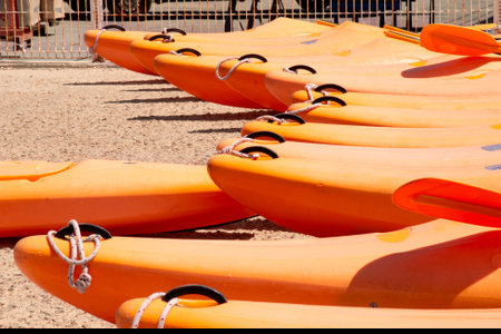 group of waterproof dinghy kayaks lined up in the color of the year apricot crush. Sports boats on the coast close-up.の写真素材