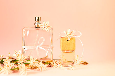 A bottle of perfume, bottles of aromatic oil with a festive ribbon with peach fuzz colored...