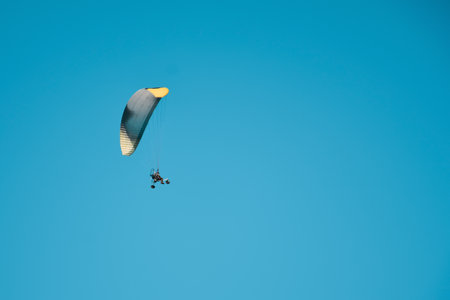 Paraglider flies with a parachute on an air motorcycle with a propeller. Man paragliding with motorized trike under clear sky. air sportsの写真素材