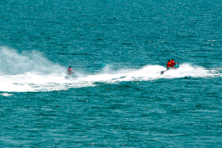 Two jet skis with water wake and spray racing across the ocean. Water transport, summer fun, water sportの写真素材
