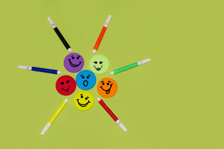 Colorful emoticons arranged in a circle with markers on a bright green background. Creativity, fun, positive, back to school, play, collaborative education, icon set, smilesの写真素材