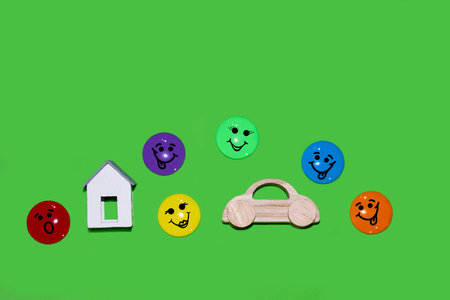 Wooden toy car and house surrounded by colorful emoticons.の写真素材