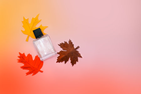 Glass perfume bottle on pastel background with autumn leaves handmade fabric, autumn decorの写真素材