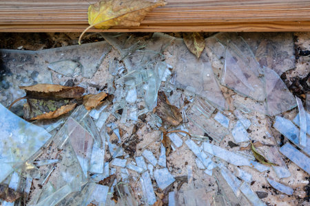 Shards of a broken window with a part of a wooden frame on concreteの写真素材