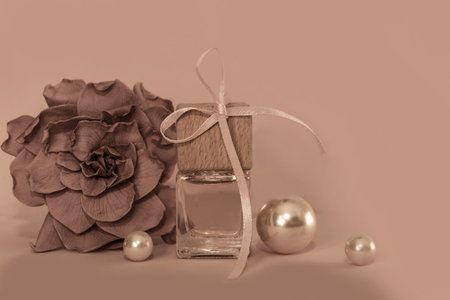 Perfume bottle with ribbon, camellia flower in the color of the year 2025 mocha mousse in tones soft brown, coffee color. Gift card for Mother's Day. Presentation of cosmetics as a giftの写真素材