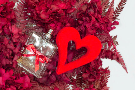 Background of hydrangea and fern flowers with a gift bottle of perfume and a decorative heart....