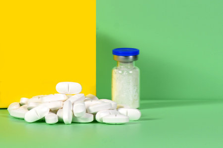 Stack of white tablets and medical vial with medicinal powder for saline injection. for advertising...
