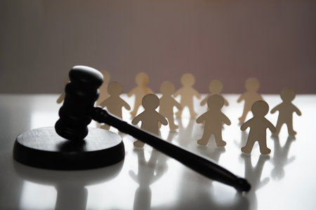 A judges gavel lies in front of a group of human figures. legal decision, lawsの写真素材