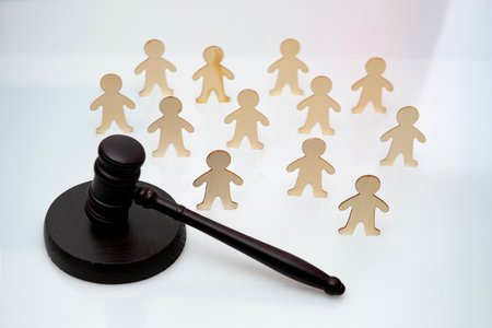 A judges gavel lies in front of a group of human figures. legal decision, lawsの写真素材