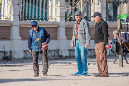 Three elderly men in a park playing petanque with metal balls on a sunny day. Life and pastime of retirees. Active lifestyle, Leisureの写真素材