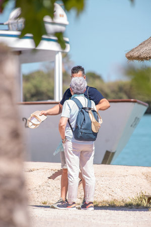 Elderly woman tourist talks to a middle-aged male guide near a pleasure boatの写真素材