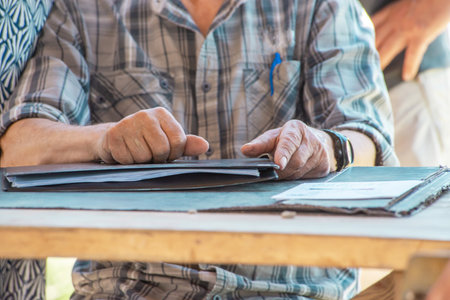 Elderly man hands holding folder and documents on work desk. Retirement lifestyle. Pension reform. Old man at work. Accounting and statistics of investments and expenses in agricultureの写真素材