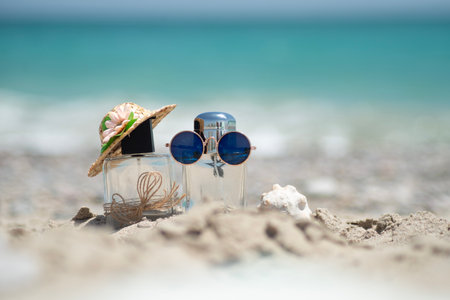 Concept of tourist VACATION on the beach with Perfume bottles in a hat and glasses on the sand...