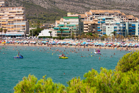 Crowded beach with colorful umbrellas,people swimming,palm, hotels in the heat.の写真素材