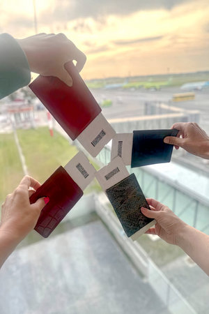 Four people holding passports and boarding passes at the airport terminal