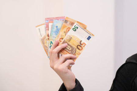 A man holding several euro banknotes. Showing off money, suggesting earnings and investments....
