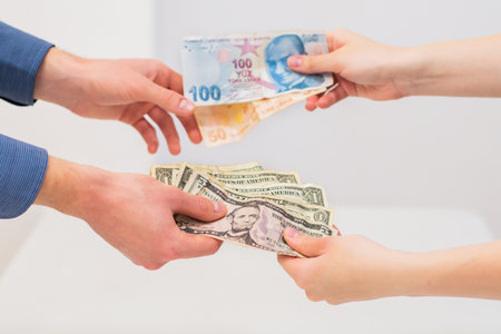 Hands of a woman and a man exchanging Turkish lira and dollar banknotes in a financial transaction....