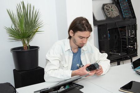 A technician repairs computer equipment using electronic components and tools. Electronics, hardware, workplaceの写真素材