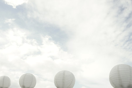 White paper lanterns appear in soft focus against a cloudy skyの写真素材
