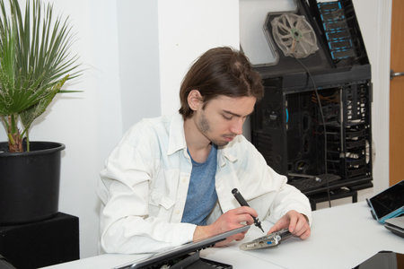 A technician repairs computer equipment using electronic components and tools. Electronics, hardware, workplaceの写真素材