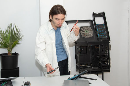 A technician repairs computer equipment using electronic components and tools. Electronics, hardware, workplaceの写真素材
