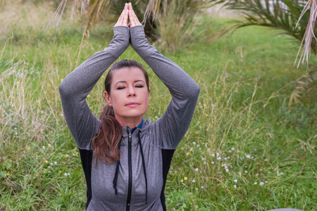 woman doing morning exercises in a park. Doing yoga. Active recreation, meditation, and wellness.の写真素材