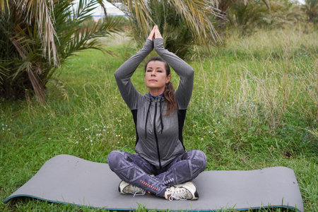 woman doing morning exercises in a park. Doing yoga. Active recreation, meditation, and wellness.の写真素材
