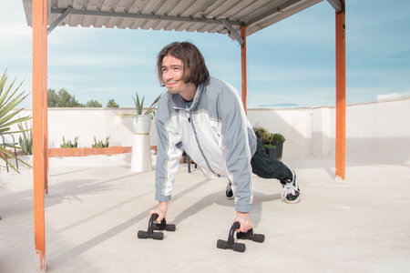 Man exercising on a rooftop using dip bars. Outdoor activity, home gym, calisthenics. Outdoor workout. Fitness, lifestyle, and wellnessの写真素材