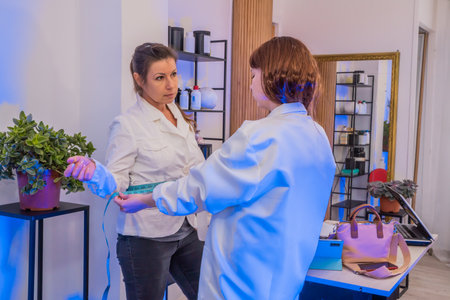 A healthcare professional measures a patient's waist with a measuring tape during a health and body condition assessment sessionの写真素材
