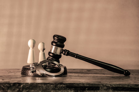 Judge's gavel with handcuffs and human figures. Legal justice, the concept of court, the symbol of law, crime and punishment, authority and the justice system, and law enforcementの写真素材