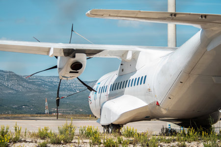 A turboprop cargo-passenger aircraft, side view from the tail, parked on an airport airfield for maintenance. airline transportationの写真素材